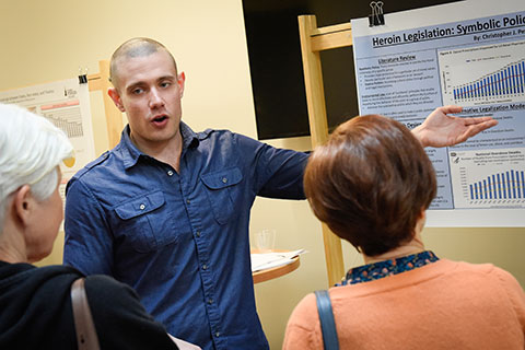 A student presents his research during a poster presentation.