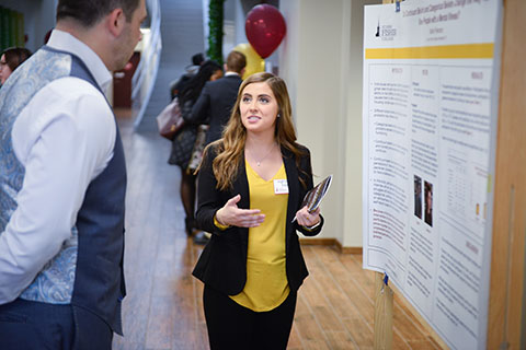 A student presents her research in the form of a poster presentation.