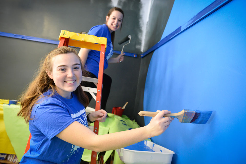 Two students paint a classroom during the annual Color the Roc event.