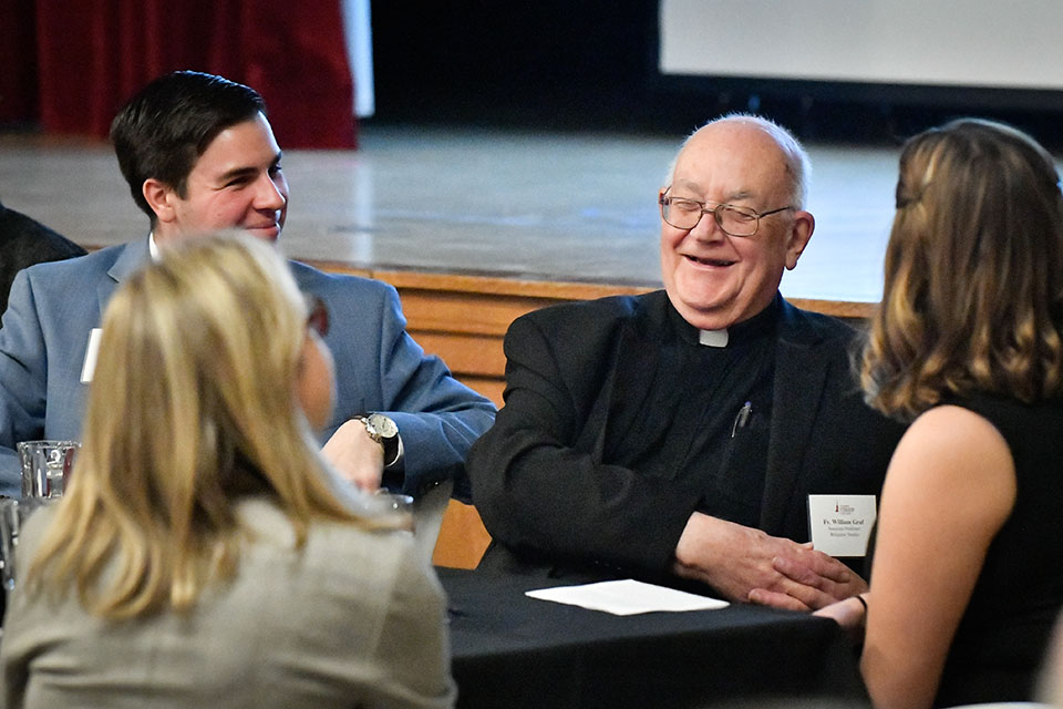 Fr. Graf, Fisher's first endowed professor, speaks with several students.
